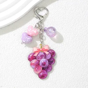 Gros plan d'un joli porte-clés raisin violet avec des breloques cœur roses.