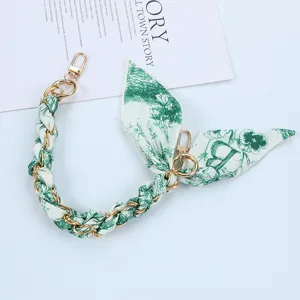 Close-up of green floral scarf phone lanyard with gold chain and double clasps