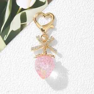 Detail view of a cute pink strawberry keychain with a crystal bow and heart-shaped clasp