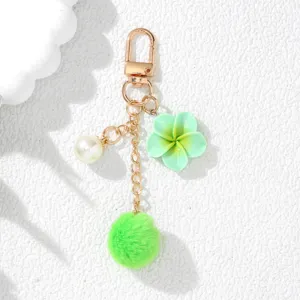 Detailed view of a mint green resin flower and pom-pom keychain with a white pearl charm.