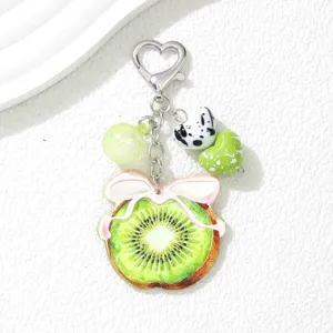 Détail d'un joli porte-clés tranche de kiwi avec fermoir cœur et perles décoratives marbrées