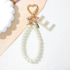 Detailed view of pearl letter L charm on a heart-shaped golden keychain