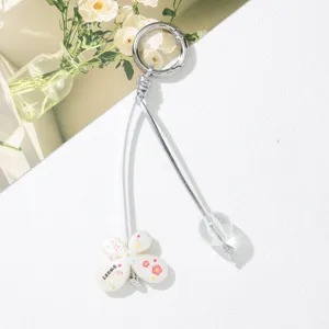 Close-up of a cute white flower charm and clear bead on a silver cord keychain.