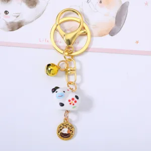 Close-up detail of cute ceramic cow keychain with golden bell and Chinese zodiac charm