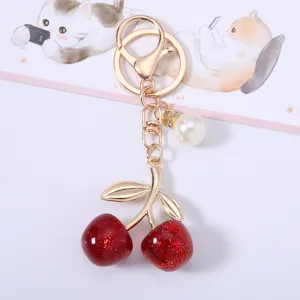 Close-up of glittery red acrylic cherry keychain with pearl charm and gold-tone clasp