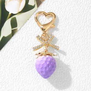 Detailed view of sweet purple strawberry keychain with rhinestone bow and heart clasp.
