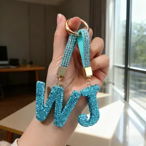 Detailed close-up of sparkling light blue rhinestone letter W and J keychain pendants.