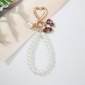 Detail view of handmade faux pearl bow keychain with heart clasp and rhinestones