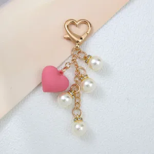 Vue détaillée d'un porte-clés à la mode avec cœur rose, perles blanches et fermoir doré