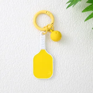 Gros plan d'un porte-clés raquette de pickleball jaune avec un charme de balle assorti