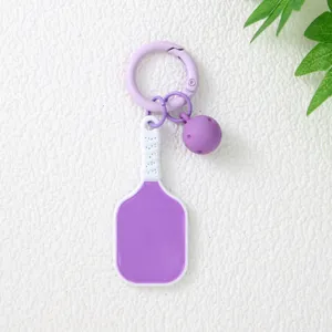 Gros plan détaillé d'un joli porte-clés raquette de pickleball violet avec mini balle