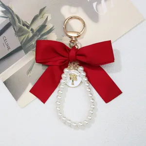 Close-up of elegant large red bow keychain with pearl loop and golden trend charm