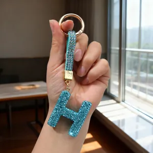 Close-up of a luxury blue rhinestone letter H keychain with a crystal-studded strap