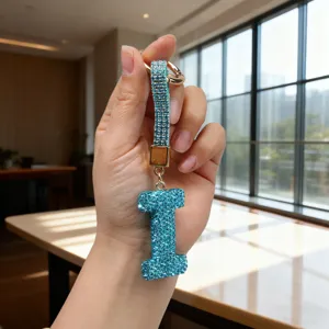 Macro shot of a sparkling blue rhinestone letter I keychain held in hand for detail.
