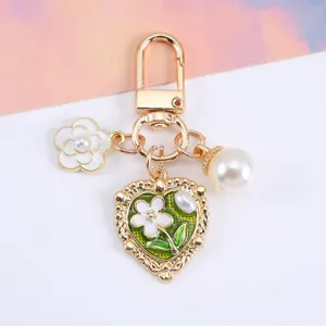 Detail view of heart-shaped pendant keychain with white flower and elegant pearl accents