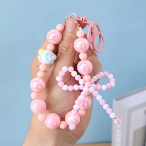 Detailed view of pink bow beaded keychain with heart charm detail and glossy pearls.
