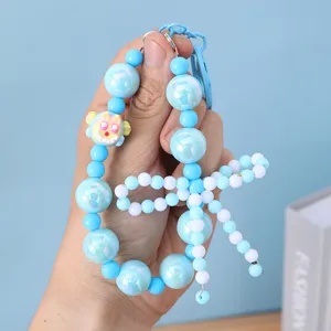 Close-up view of a blue beaded phone charm featuring a delicate hand-made bow detail