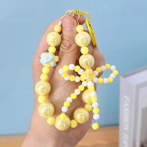 Close-up of yellow beaded bow phone charm with a tiny heart accessory for girls.