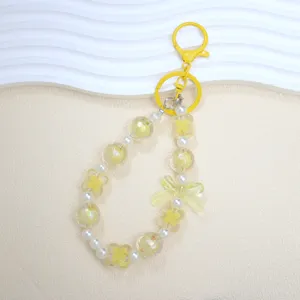 Close-up detail of cute yellow beaded phone strap featuring lucky clover and bow charms