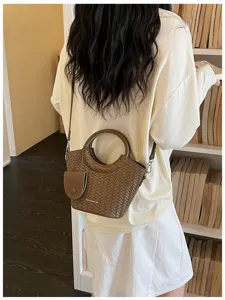 Detailed view of a brown woven texture bucket bag with round handles and a crossbody strap.