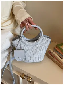 Detailed view of a light blue woven texture bucket bag featuring a unique round handle design
