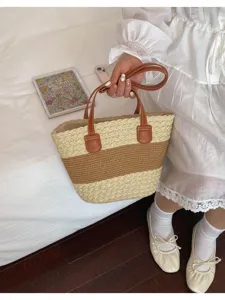 Détail du sac cabas en paille avec motif bicolore marron et poignées en cuir.