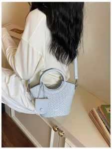Elegant light grey woven texture bucket bag with round handle shown worn by a model