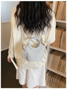 Modern woven texture bucket bag with round handle and charm shown in library setting