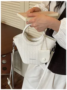 Detailed view of white woven bucket bag featuring embossed texture and a mini coin pouch