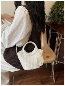 White woven texture bucket bag with round handles shown in a chic lifestyle setting