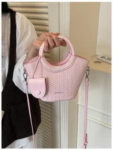 Pink woven texture bucket bag with circular handle and adjustable shoulder strap detail