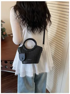 Stylish black woven texture bucket bag with round handle and adjustable crossbody strap