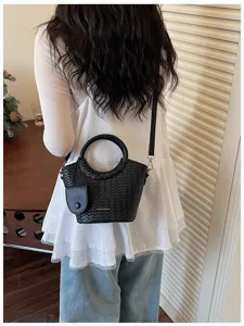 Stylish black woven bucket bag with round handle shown on a model for lifestyle detail