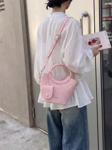 Elegant pink woven bucket bag with circular handle and adjustable shoulder strap