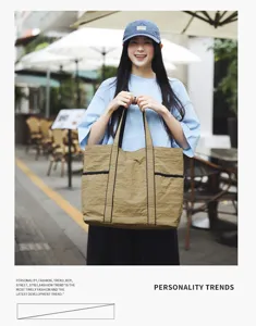 Lifestyle view of a large khaki nylon commuter tote bag held by a model in a street setting