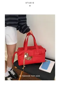 Detail of red litchi-texture leather tote bag with horse charm accessory.