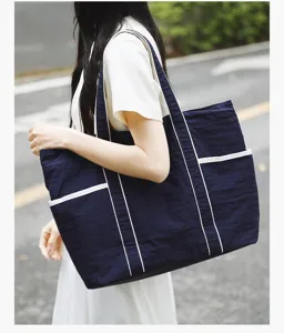 Outdoor lifestyle view of a large capacity navy nylon tote bag with white trim