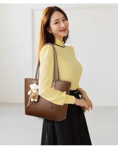 Professional brown leather tote bag with a cute bear charm carried by a female model.