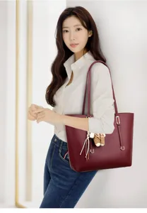 Large burgundy leather tote bag for women worn by model in casual office attire