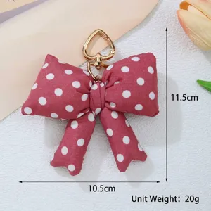 Macro view of red polka dot padded bow keychain with heart clasp and size markings