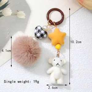 Detailed view of cute flocked white bear keychain with brown pom pom and star charms