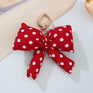 Detailed shot of a red and white polka dot padded bow charm with gold heart clasp