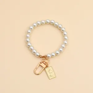 Close-up of pearl bead keychain with gold Elizabeth II pendant and lobster clasp.