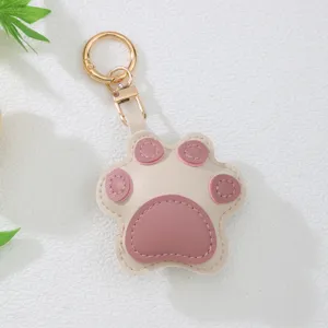 Detail of a cute pink and beige leather cat paw keychain with high-quality gold hardware