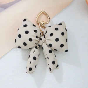 Close-up of a stylish cream polka dot bow accessory with a gold heart-shaped clasp.