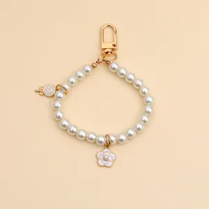 Close-up detail of vintage style pearl keychain with gold flower and lollipop charms
