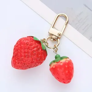 Cute strawberry keychain with two realistic fruit charms and golden clasp for bags.