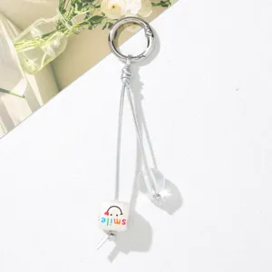 Detail view of cute bag charm featuring a 'smile' cube bead and silver ring