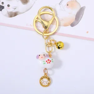 Detailed view of handmade ceramic sheep keychain with golden bell and zodiac coin charm