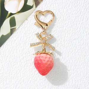 Close-up detail of a sweet pink strawberry keychain with a crystal-studded bow decoration
